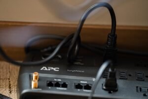 Close-up of an APC SurgeArrest power strip and surge protector with several black power cords plugged into it
