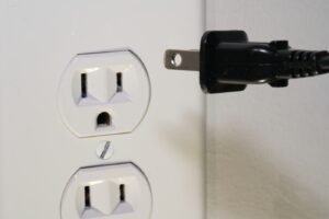 Close-up of an electrical plug in front of a wall outlet